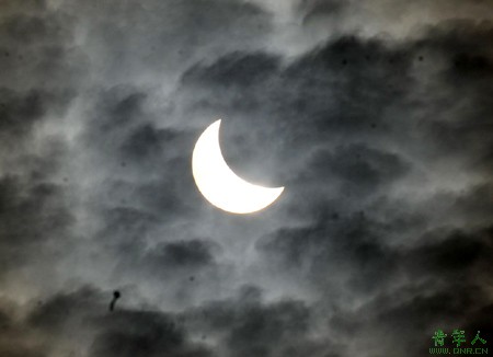 The moon passes between the sun and the earth amid clouds during a solar eclipse in Lanzhou, northwest China's Gansu province, July 22, 2009. (Xinhua)
